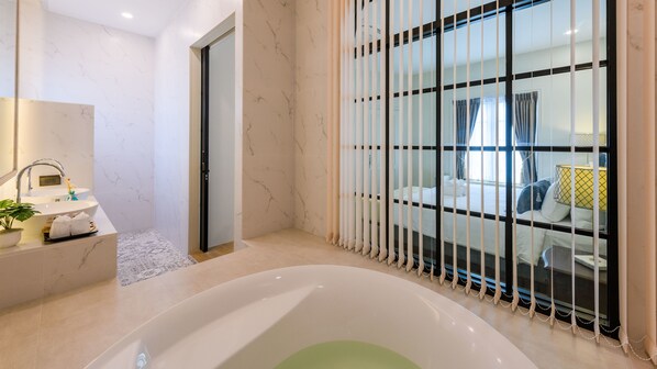 A modern bathroom with a freestanding bathtub, a sink with a mirror, and a shower area. - Villa Seville (Hua Hin)