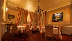 Un espace repas avec des tables et des chaises, un lustre et un tableau accroché au mur.