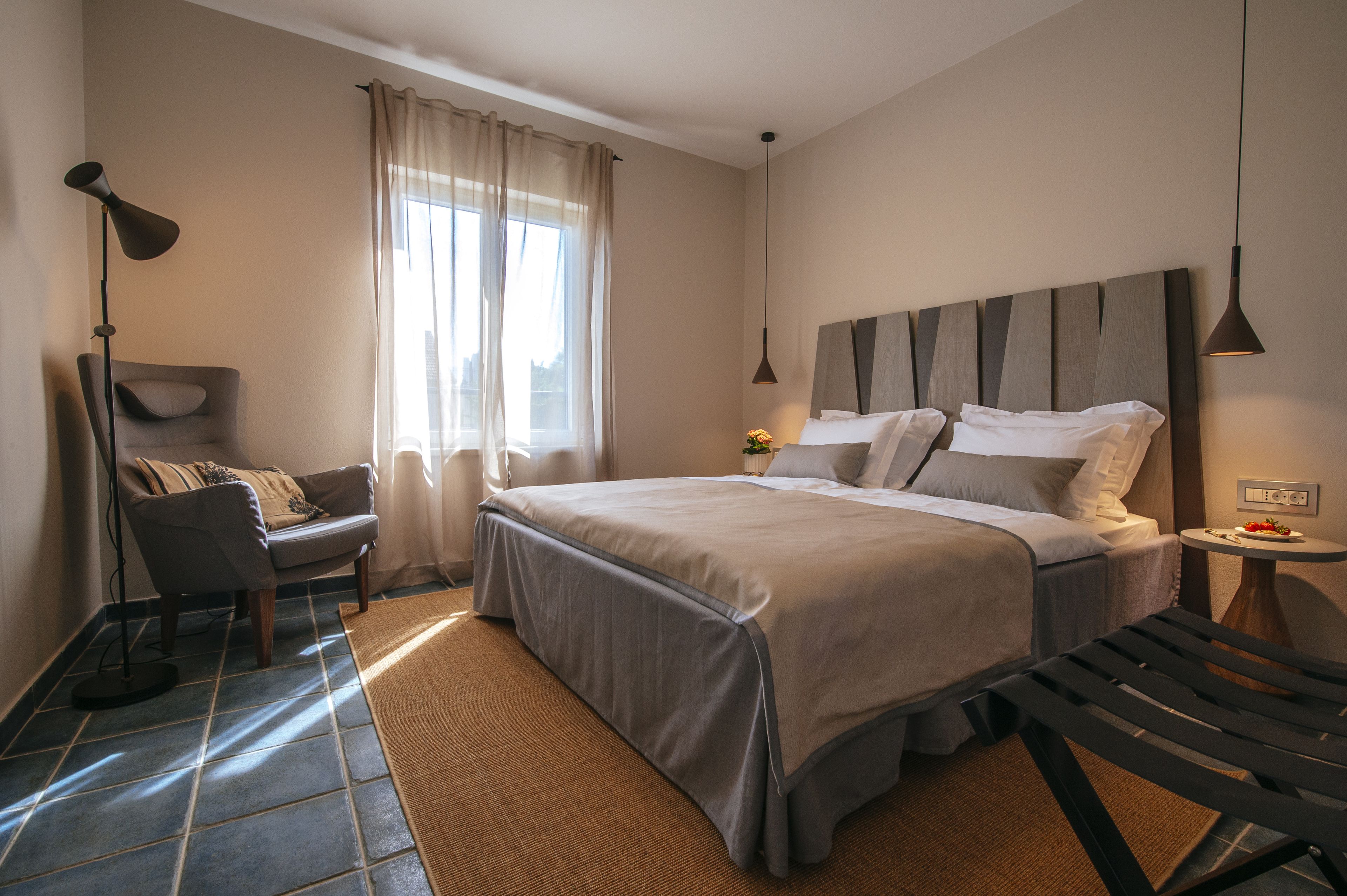 Un dormitorio con cama, una silla, un escritorio y una lámpara.