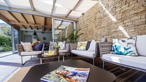 A modern living room with a magazine on a coffee table, wicker furniture, and a stone wall.