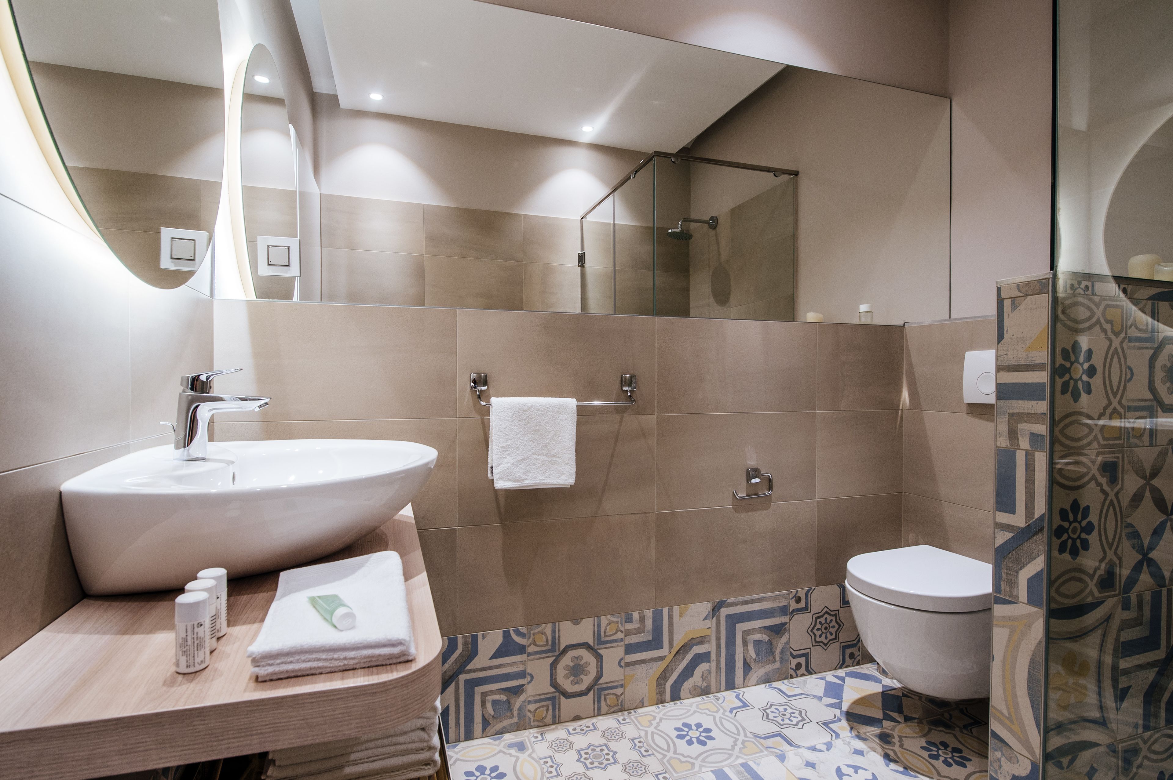 A modern bathroom with a large sink, a glass shower enclosure, and a toilet.