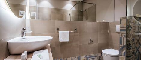 A modern bathroom with a large sink, a glass shower enclosure, and a toilet.