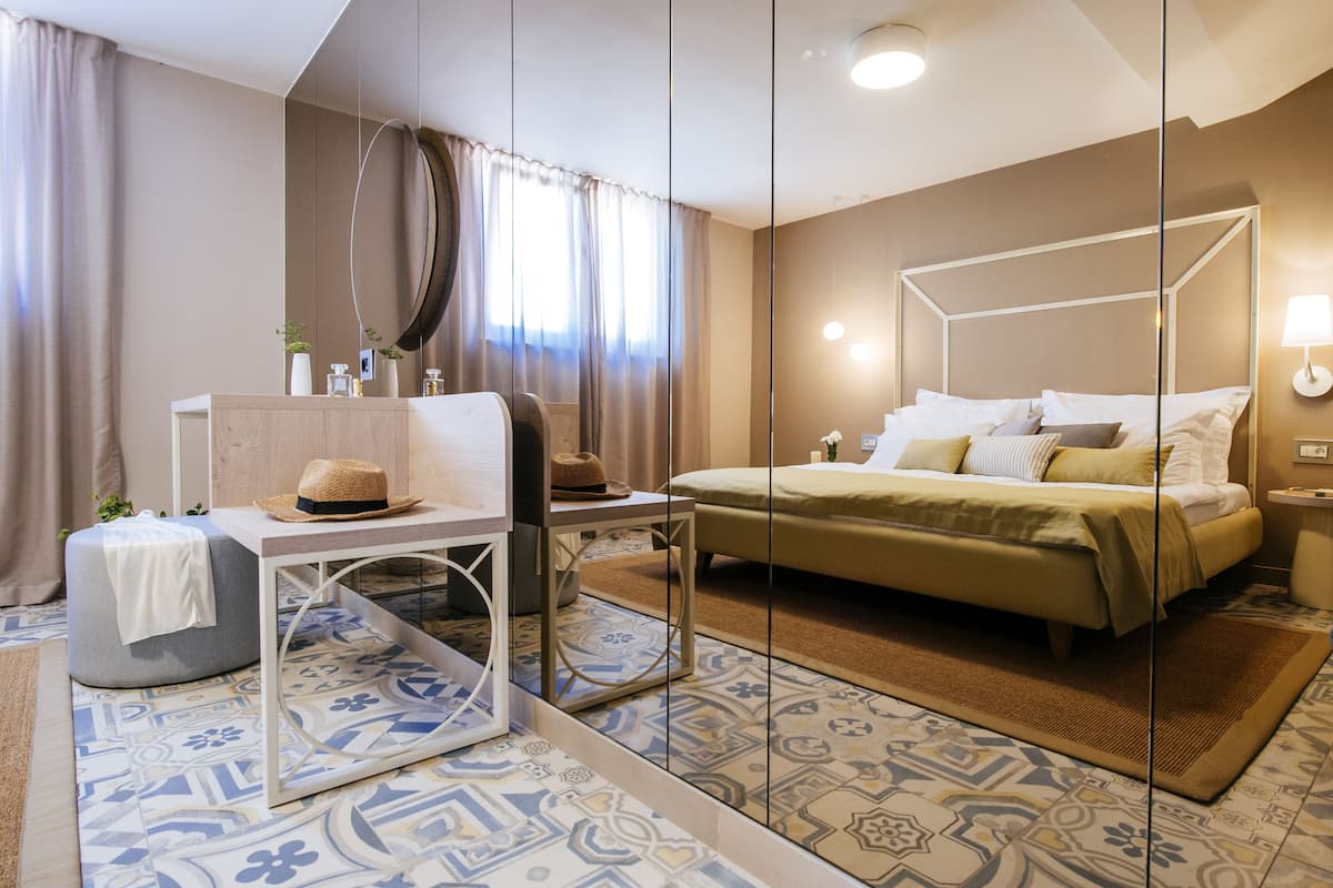 A modern hotel room with a bed, bedside table, and a mirror.
