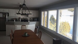 Une cuisine moderne avec des meubles blancs, un îlot central et un coin repas comprenant une table et des chaises en bois.