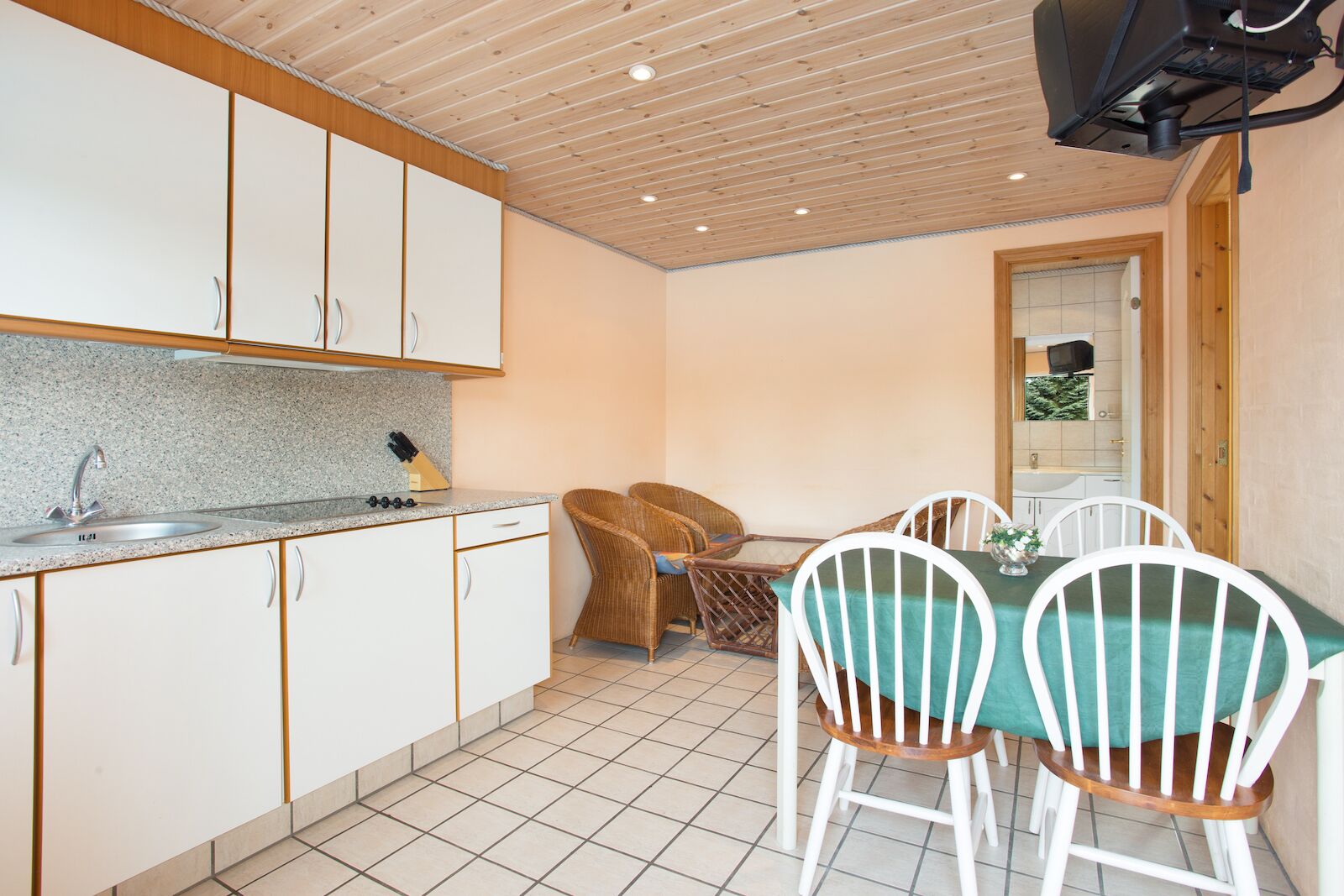 A compact kitchen with white cabinets, a granite countertop, and a dining area with a table and chairs.
