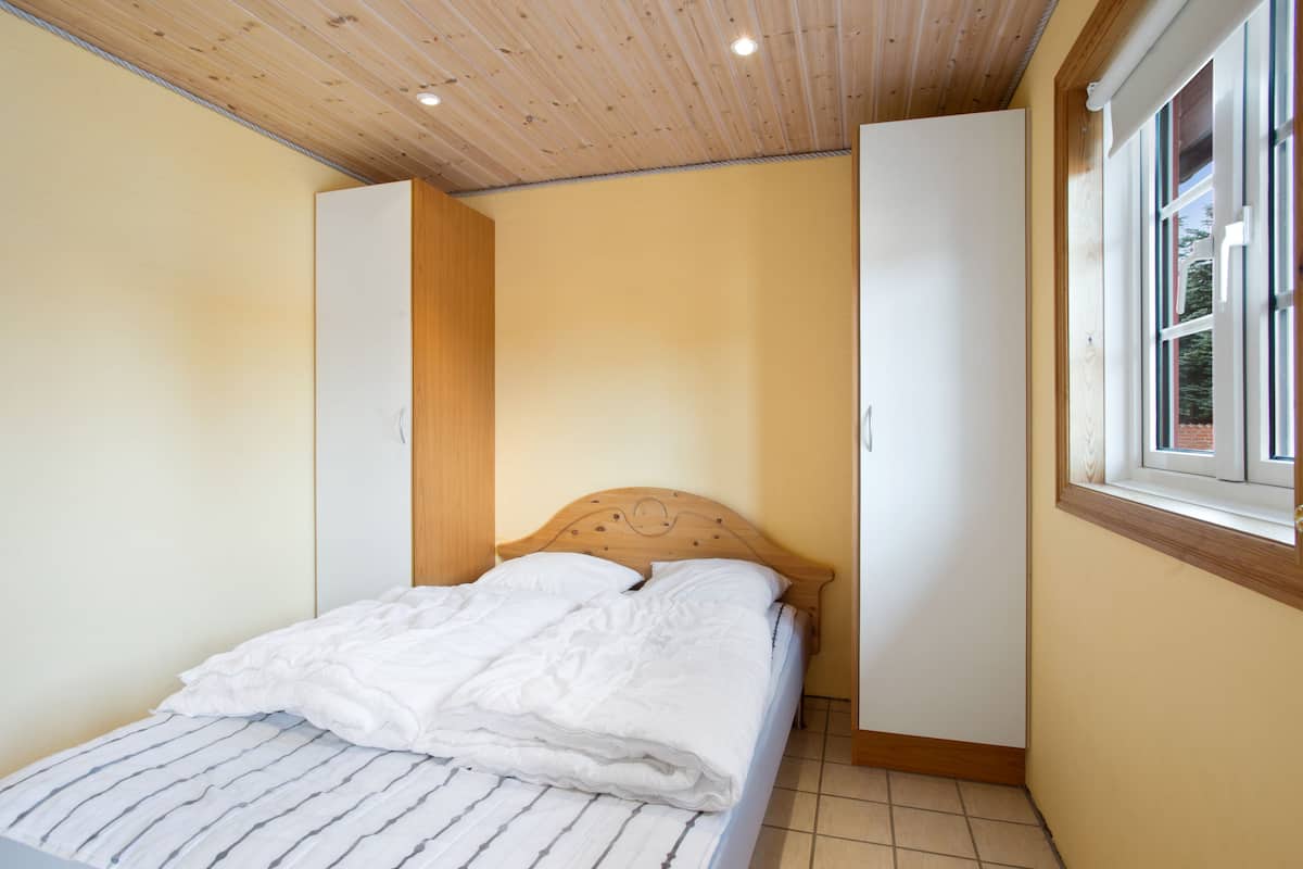 Ein Schlafzimmer mit einem Bett, Holzboden und einem Fenster.