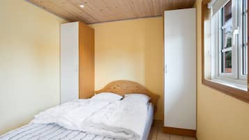 Un dormitorio con cama, techo de madera y ventana.