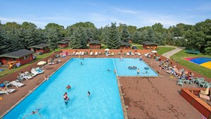 A large outdoor swimming pool surrounded by lounge chairs and small cabins. - Kongernes feriepark Camping (Graested)