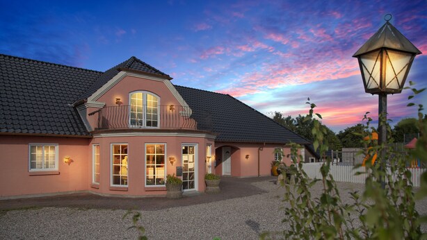 A two-story house with a gravel driveway and a white picket fence. - Kongernes feriepark Camping (Graested)