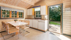 A wooden cabin with a kitchen, dining area, and a sliding glass door to the outdoors. - Kongernes feriepark Camping (Graested)