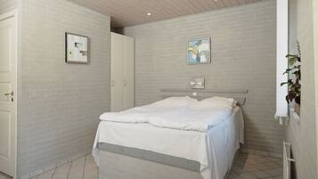 Un dormitorio con cama, puerta, luz instalada en la pared y una planta.
