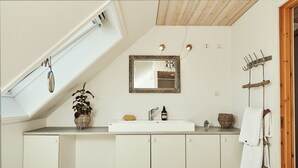 A bathroom with a white sink, a mirror, a towel rack, and a small plant. - Kongernes feriepark Camping (Graested)