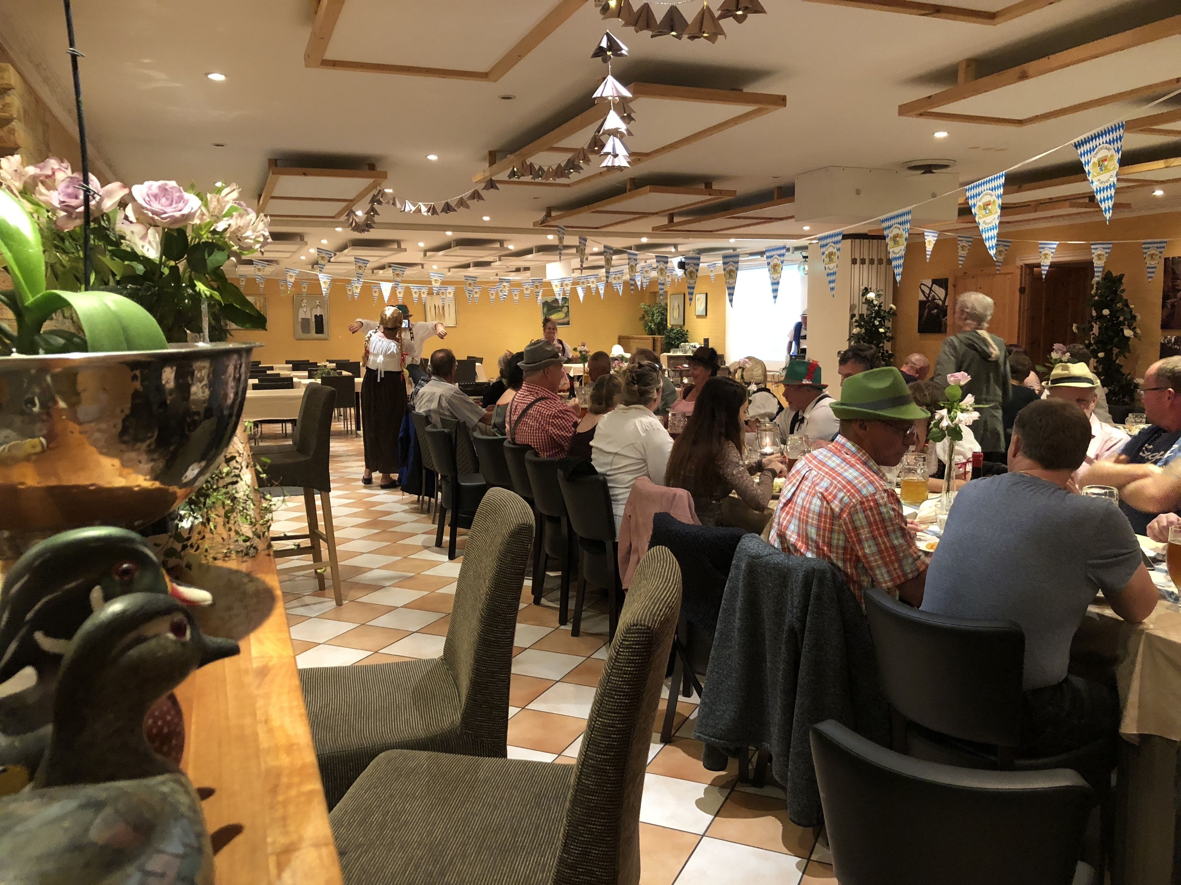 Un área de comedor con mesas y sillas, decorada con guirnaldas azules y blancas.