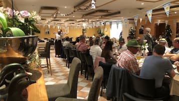 Un área de comedor con mesas y sillas, decorada con guirnaldas azules y blancas.