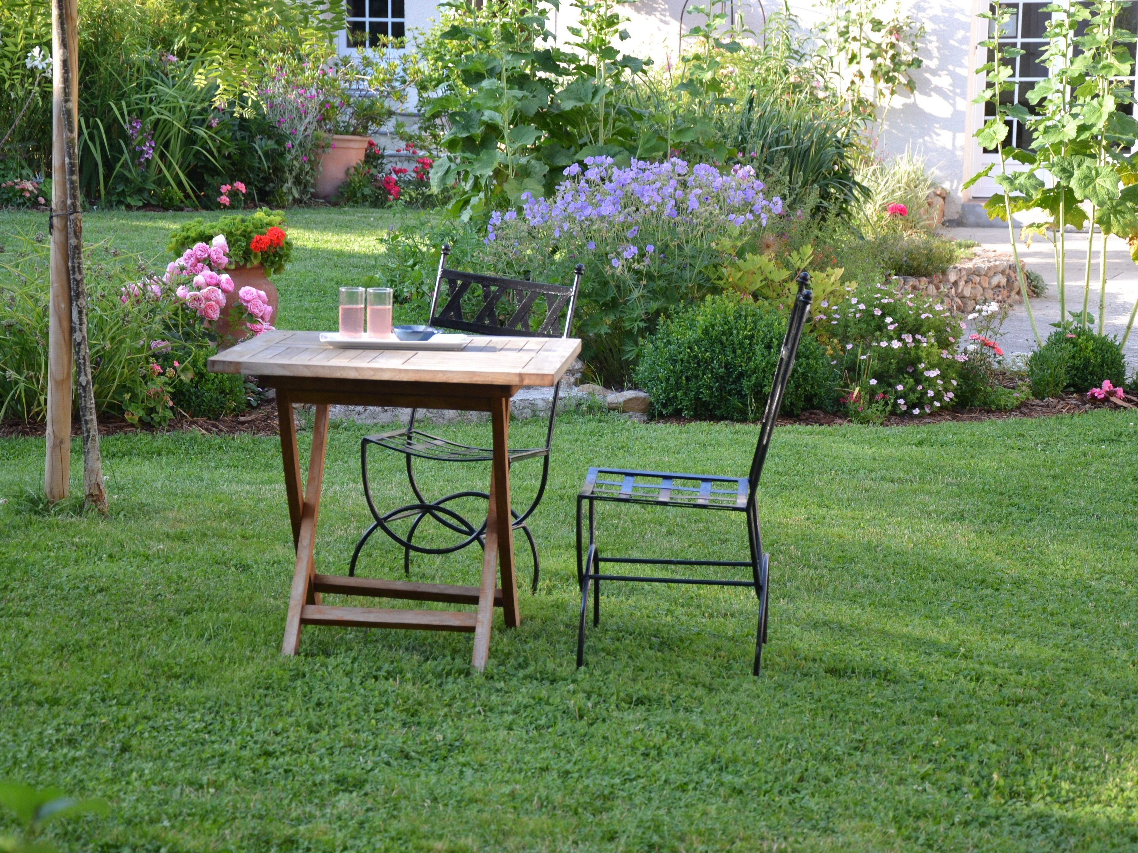 A wooden table with chairs in a garden setting.
