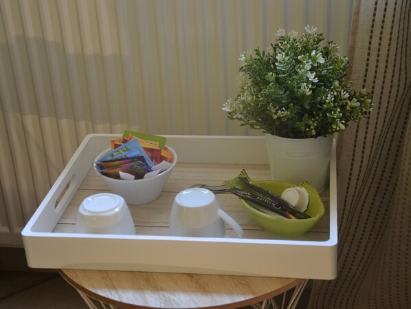 A tray with a bowl of colorful cards, a small potted plant, and two white cups. - Les Célestines (Lavannes)