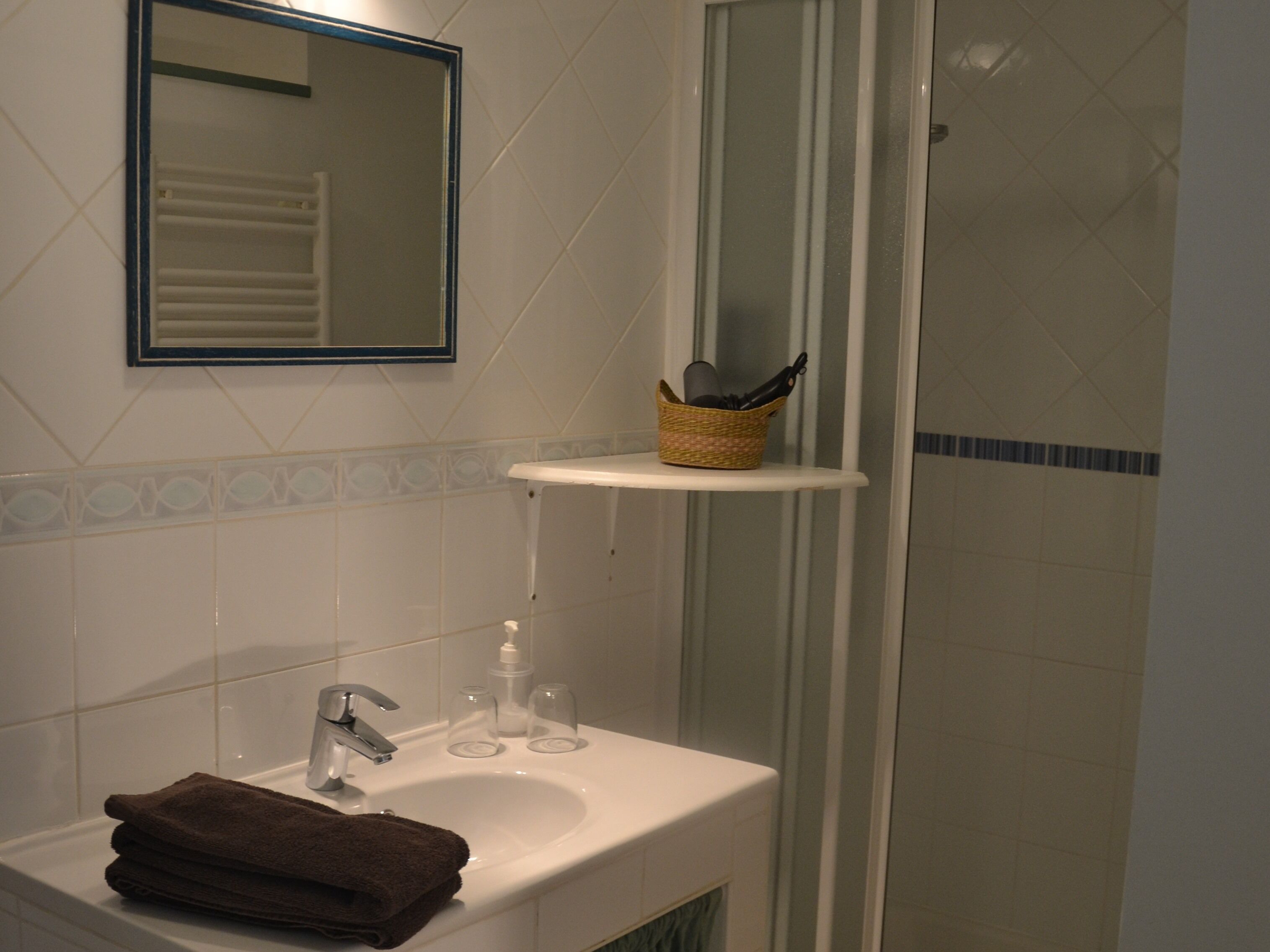 Une salle de bain équipée d’un lavabo, d’un miroir et d’une zone douche.
