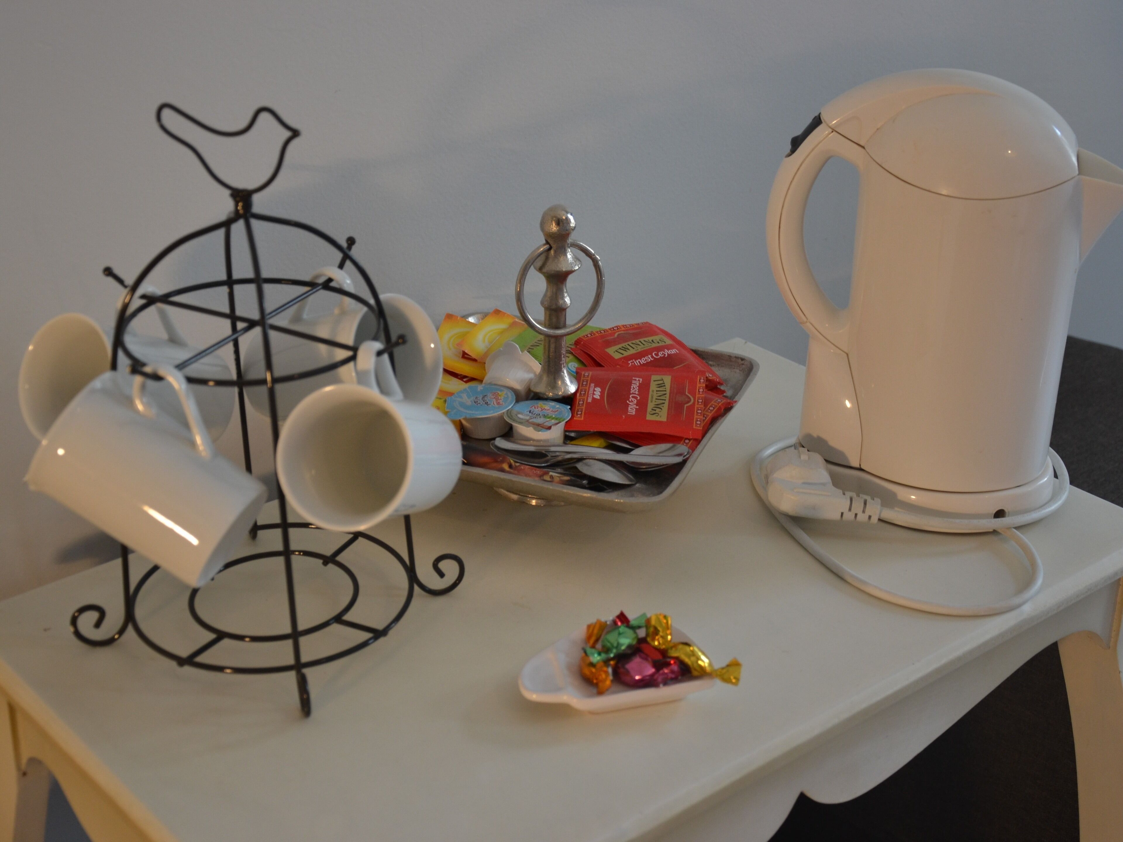 Eine Küchenarbeitsplatte mit einer Kaffeemaschine, Tassen, einer Platte mit Speisen und einer kleinen Schale mit Süßigkeiten.
