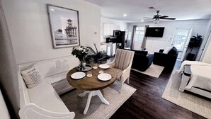A modern dining area with a round wooden table, white chairs, and a vase of flowers. - Private luxury studio- 10 mins downtown and Folly (Charleston County)