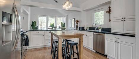 Una cocina moderna con armarios blancos, una mesa de madera y taburetes de bar.