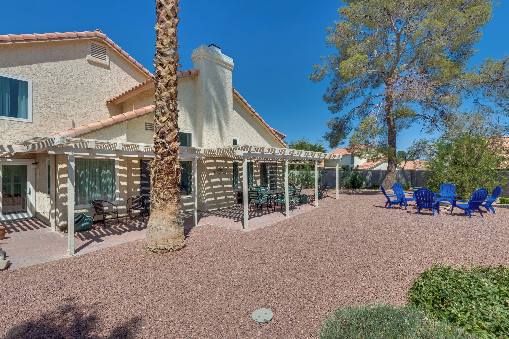 A house with a covered patio, outdoor seating, and a palm tree.