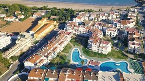 Vue aérienne d’une station balnéaire comprenant plusieurs bâtiments, une piscine et une plage.