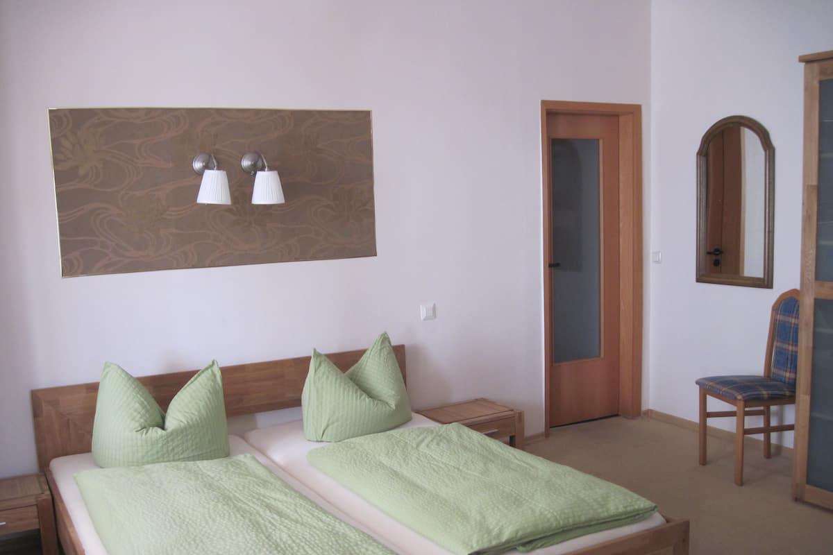 Een slaapkamer met een bed, twee nachtkastjes, een spiegel en een deur.