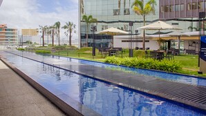 A modern hotel with a swimming pool, outdoor seating, and palm trees. - SLAVIERO Campina Grande (Campina Grande)
