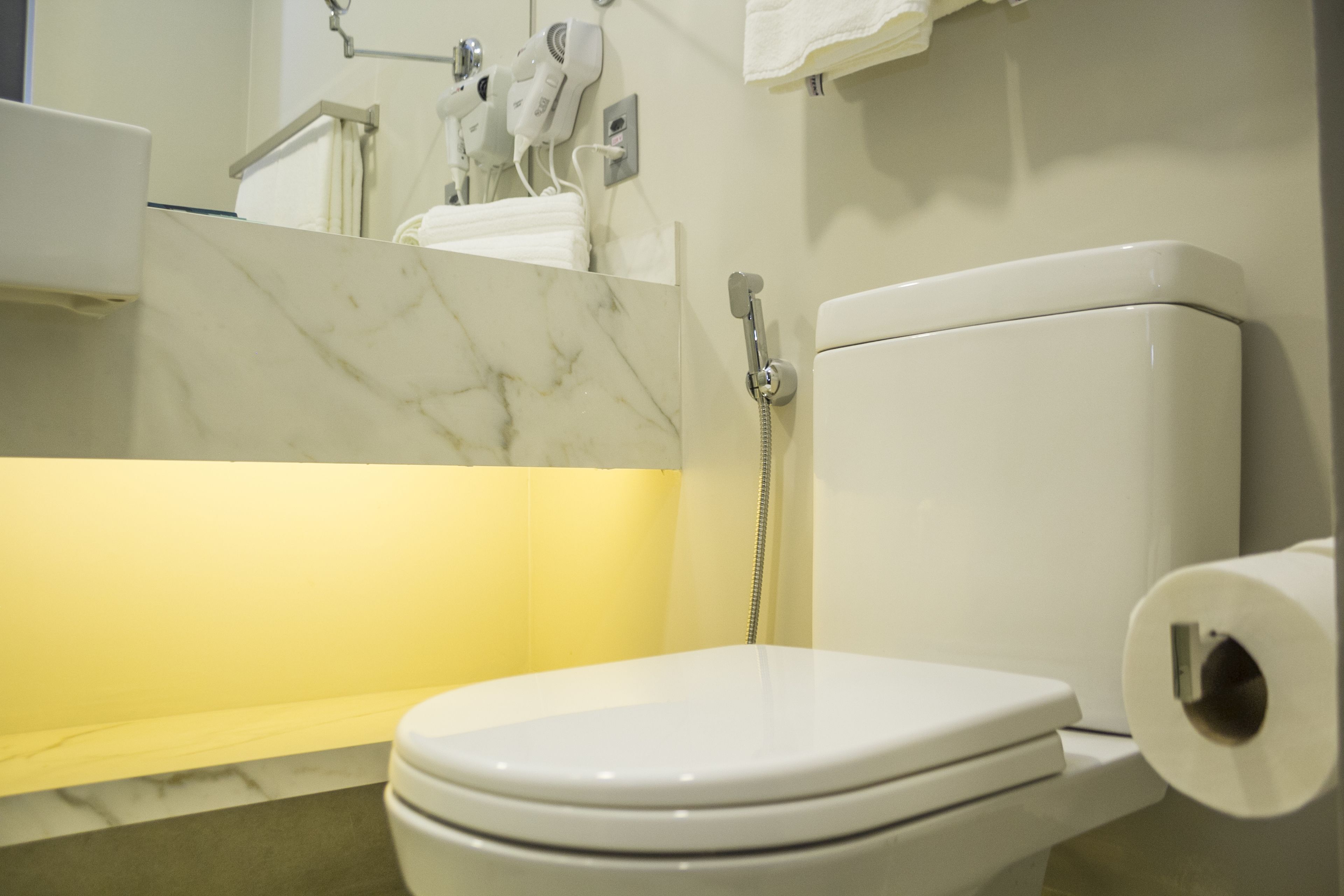 Un baño con inodoro, lavamanos de mármol y ducha.