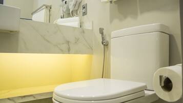 Un baño con inodoro, lavamanos de mármol y ducha.