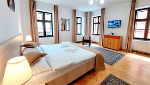 A hotel room with a bed, a chair, a television, and a wooden cabinet.