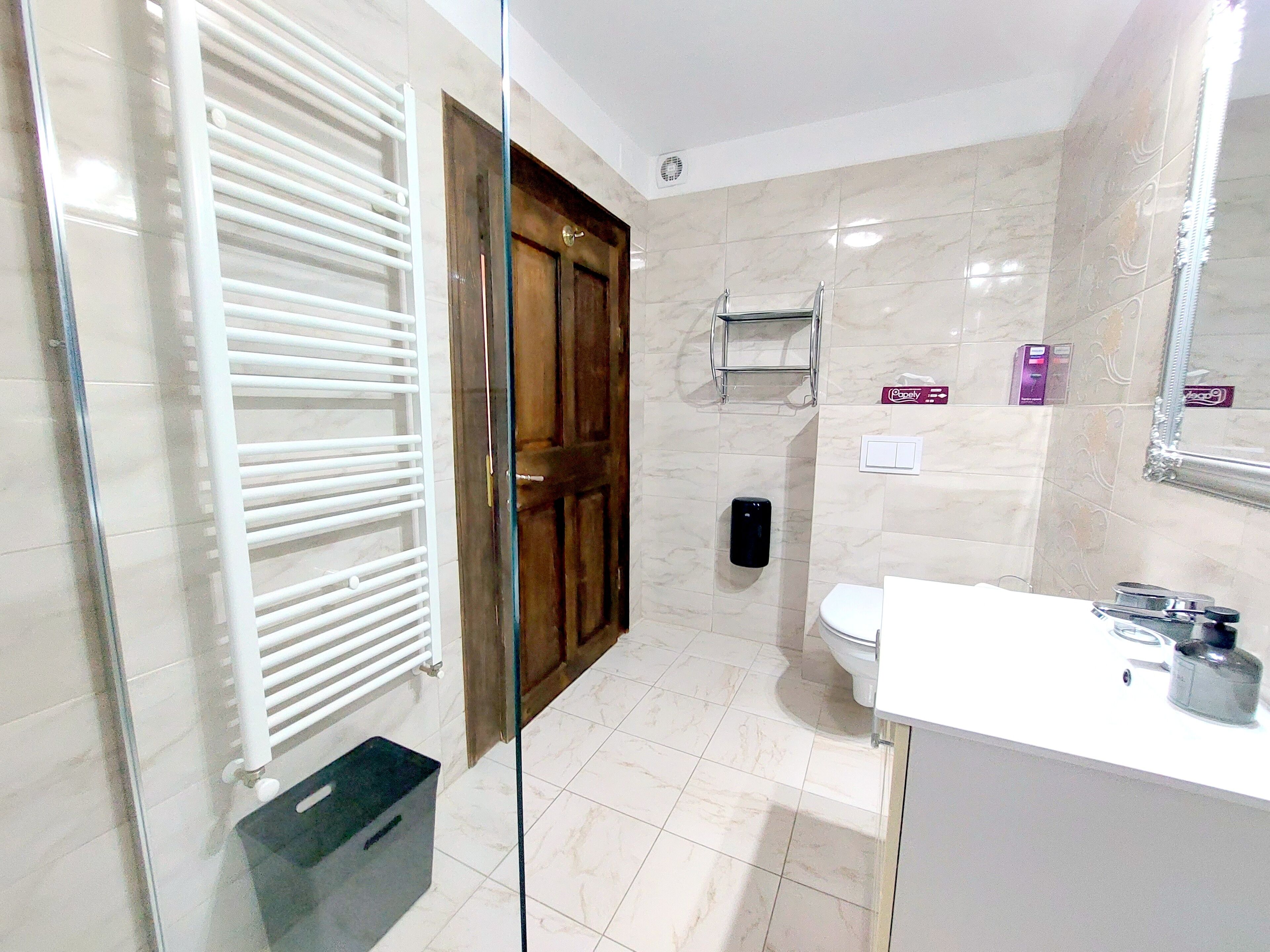A bathroom with a toilet, a sink, a mirror, a towel rack, and a shower area.