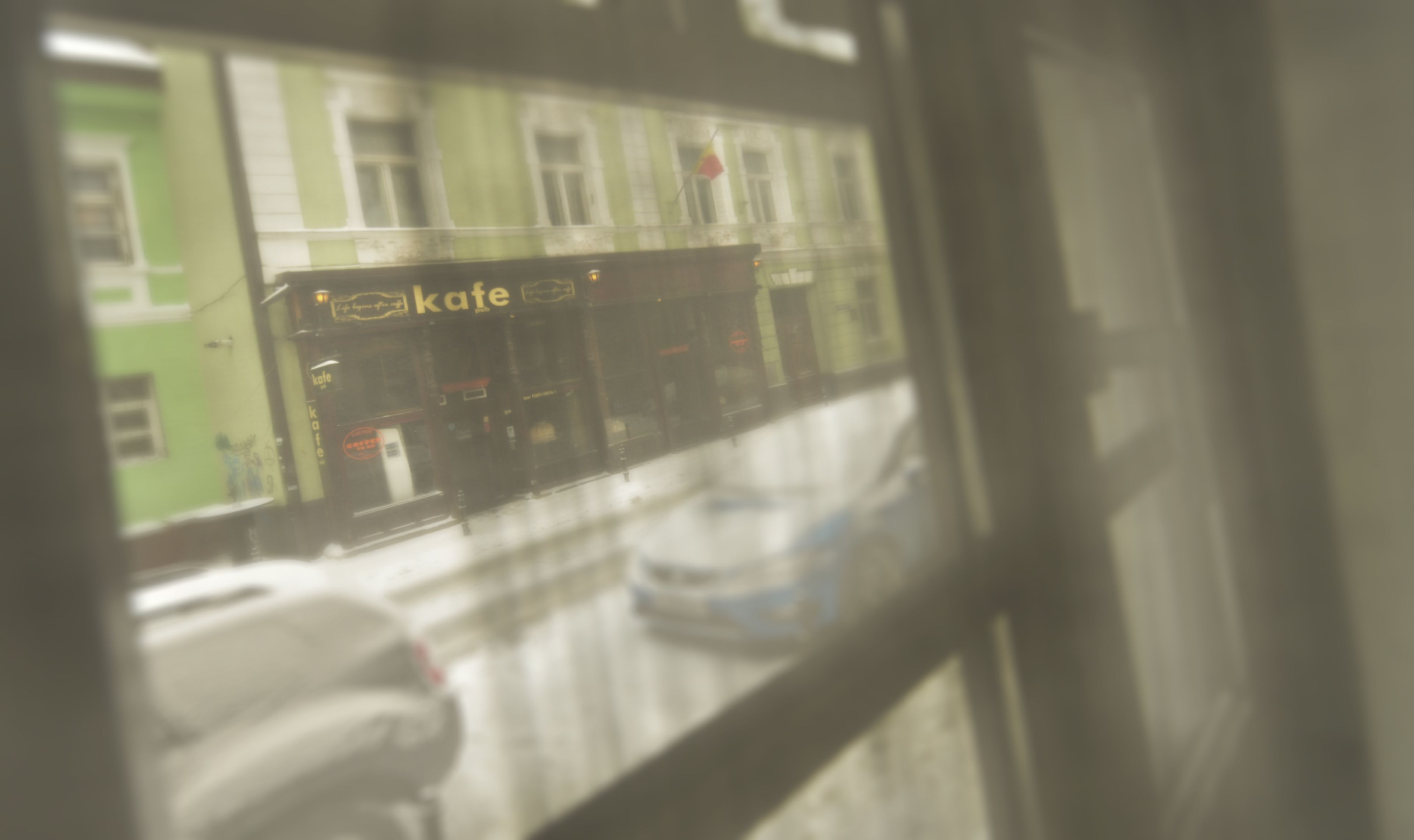 A cafe with outdoor seating visible through a window.