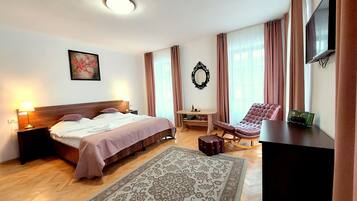 A hotel room with a bed, a desk, a chair, a TV, and a large window with curtains.