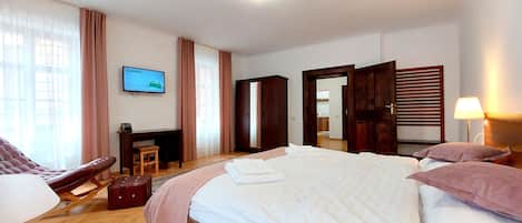 A hotel room with a bed, a desk, a chair, a television, and a wardrobe.