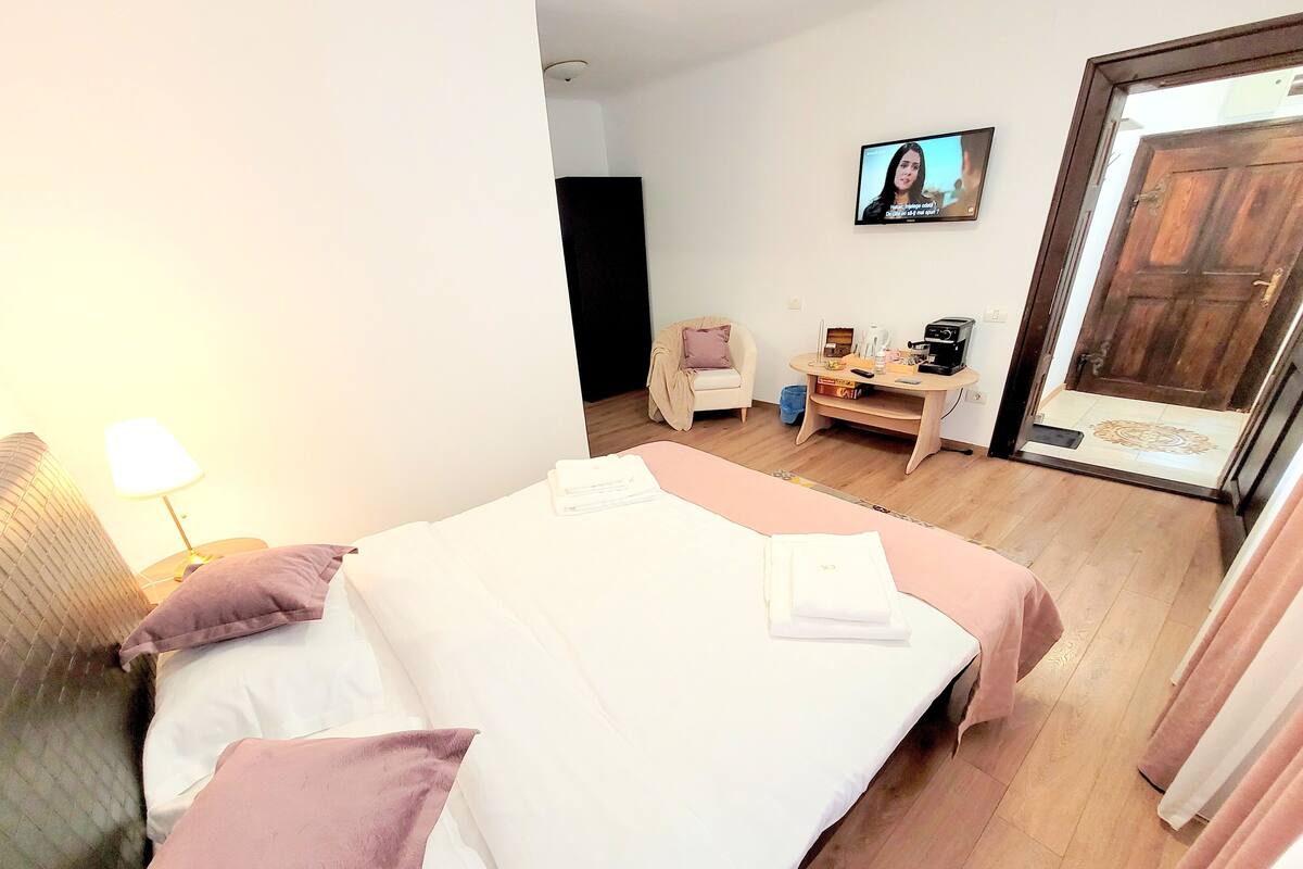 A hotel room with two beds, a desk, a TV, and a door.