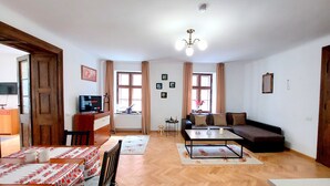 A living room with a sofa, coffee table, TV, and dining area with chairs and table.