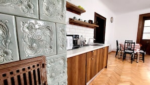 A kitchen with a herringbone wood floor, a white countertop, and a wooden cabinet with decorative tiles.