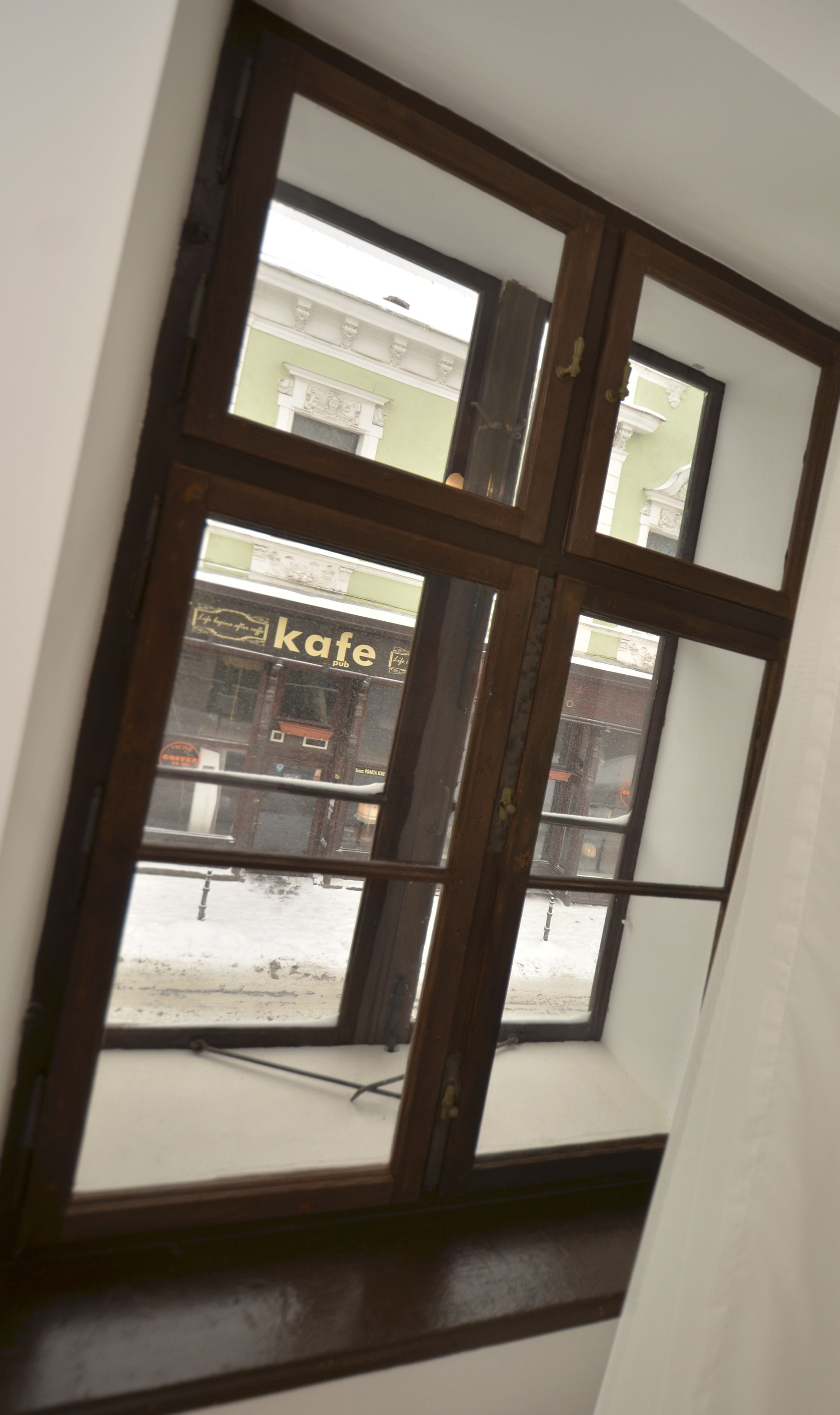 A window with a view of a building with a sign that reads "kafe pub".