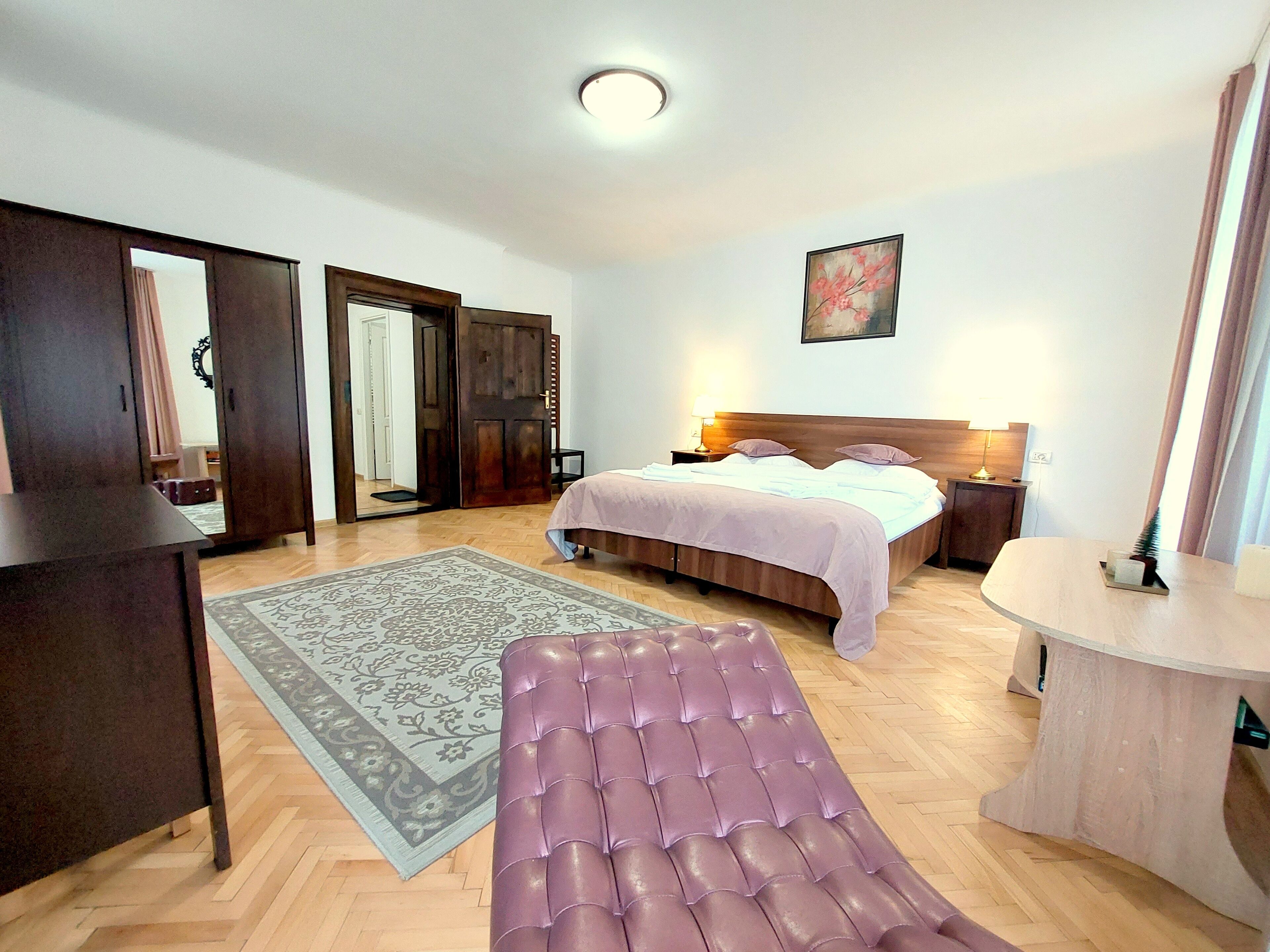 A bedroom with a bed, bedside table, lamp, and a bench.