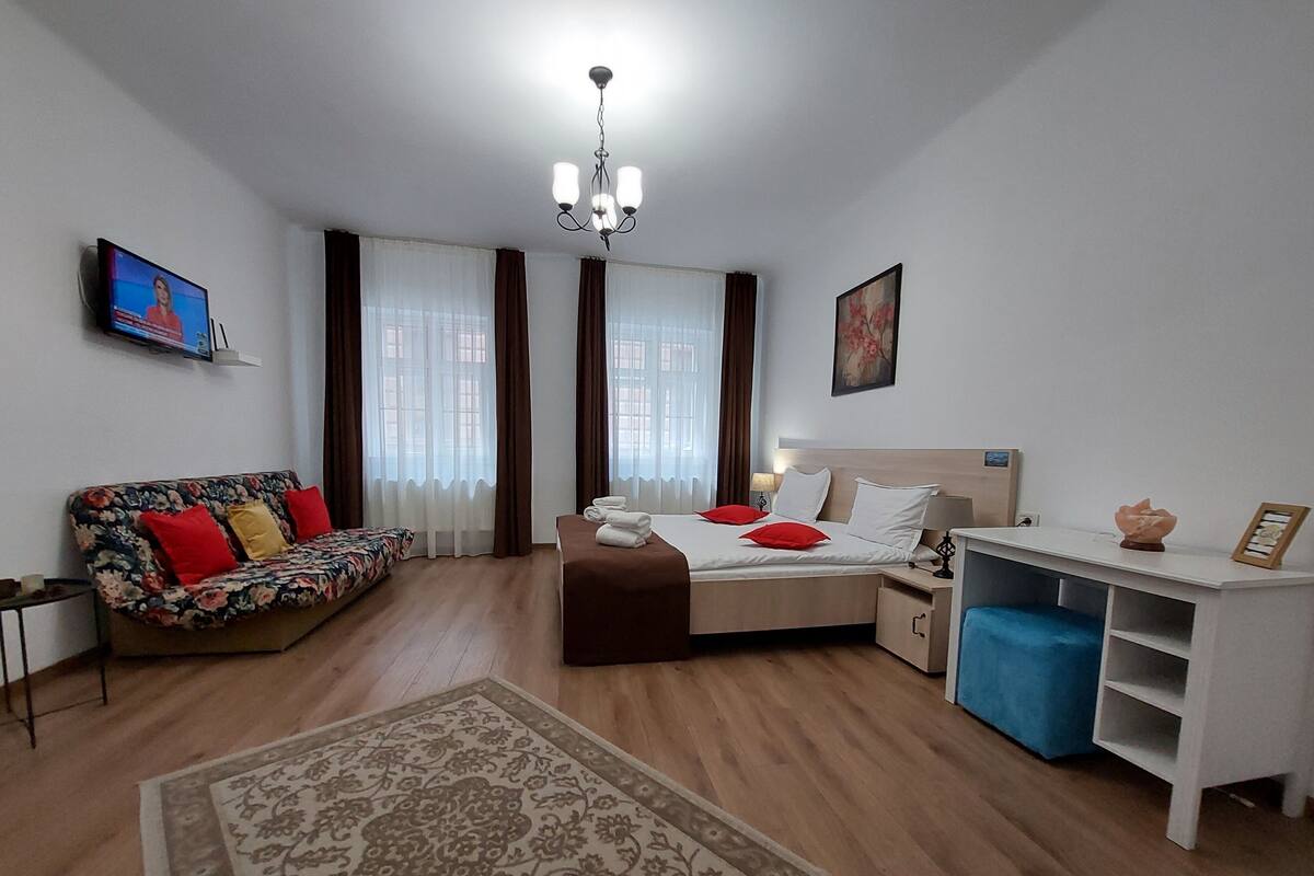 A hotel room with a bed, a desk, a sofa, and a TV.
