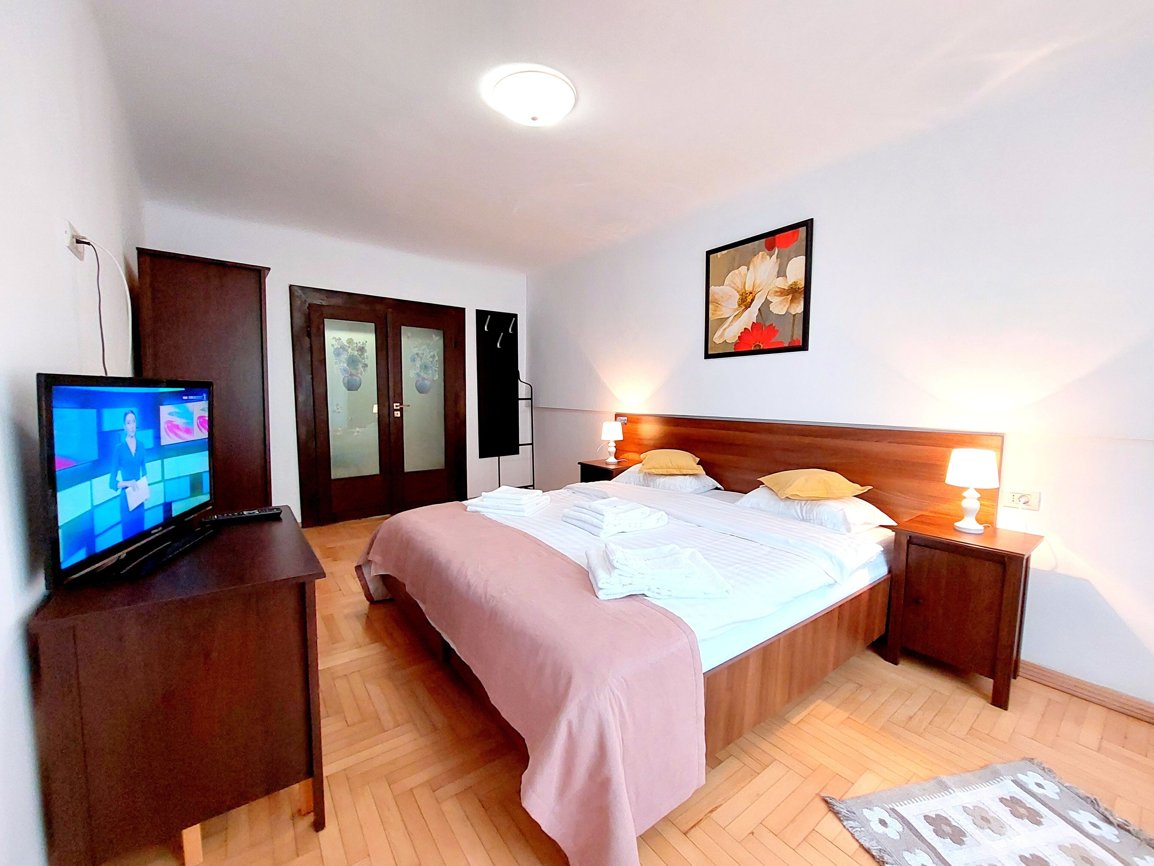 Une chambre d’hôtel avec un lit, des tables de chevet, une télévision et un tableau au mur.