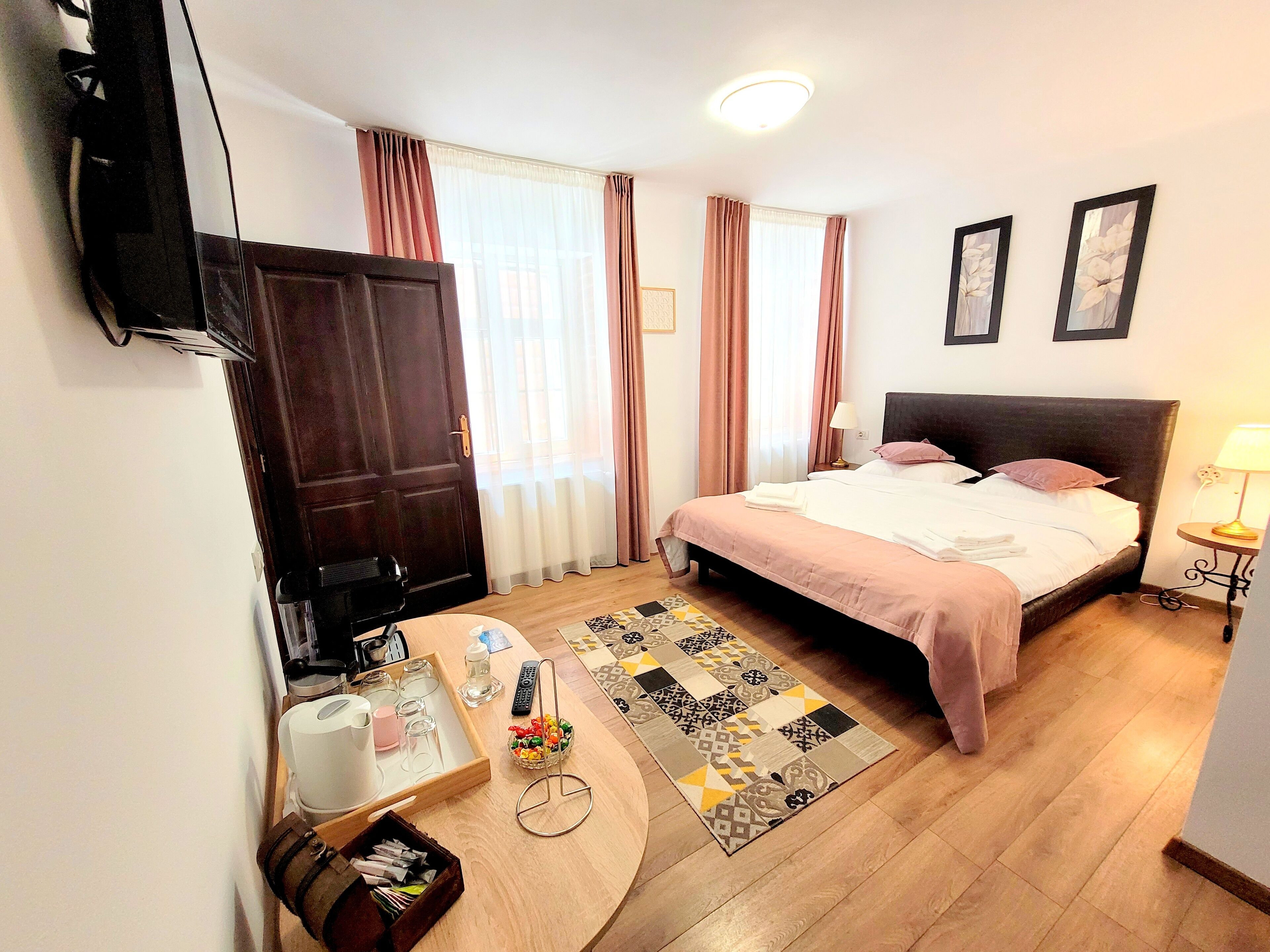 A hotel room with a bed, bedside table, lamp, and a TV mounted on the wall.