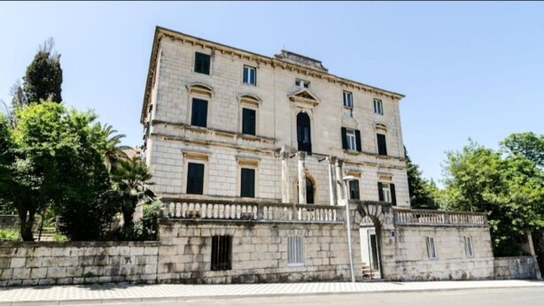 Um edifício histórico com fachada simétrica, janelas amplas e entrada central.