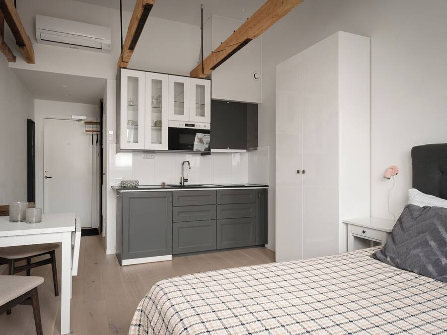 A compact bedroom with a bed, bedside table, and a small desk with a chair.