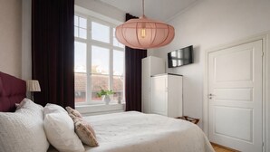 A bedroom with a bed, a TV, a wardrobe, and a window with curtains. - L Boutique Hotel (Lysekil)