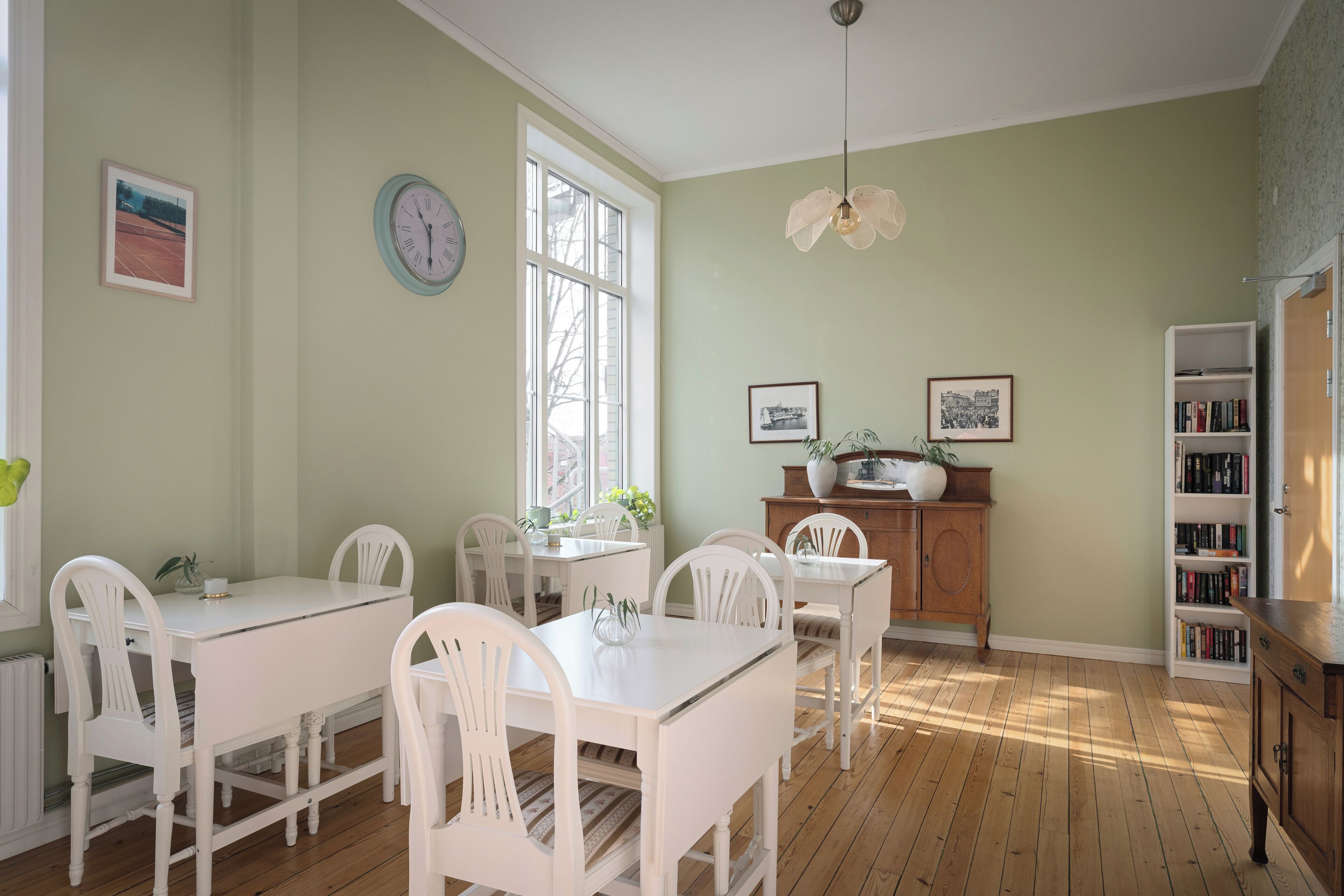 A dining room with a white table and chairs, a wooden cabinet, and a bookshelf.
