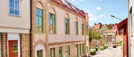 Una calle estrecha flanqueada por edificios de estilo europeo tradicional, con ventanas de arco y una combinación de fachadas de ladrillo y enlucido.