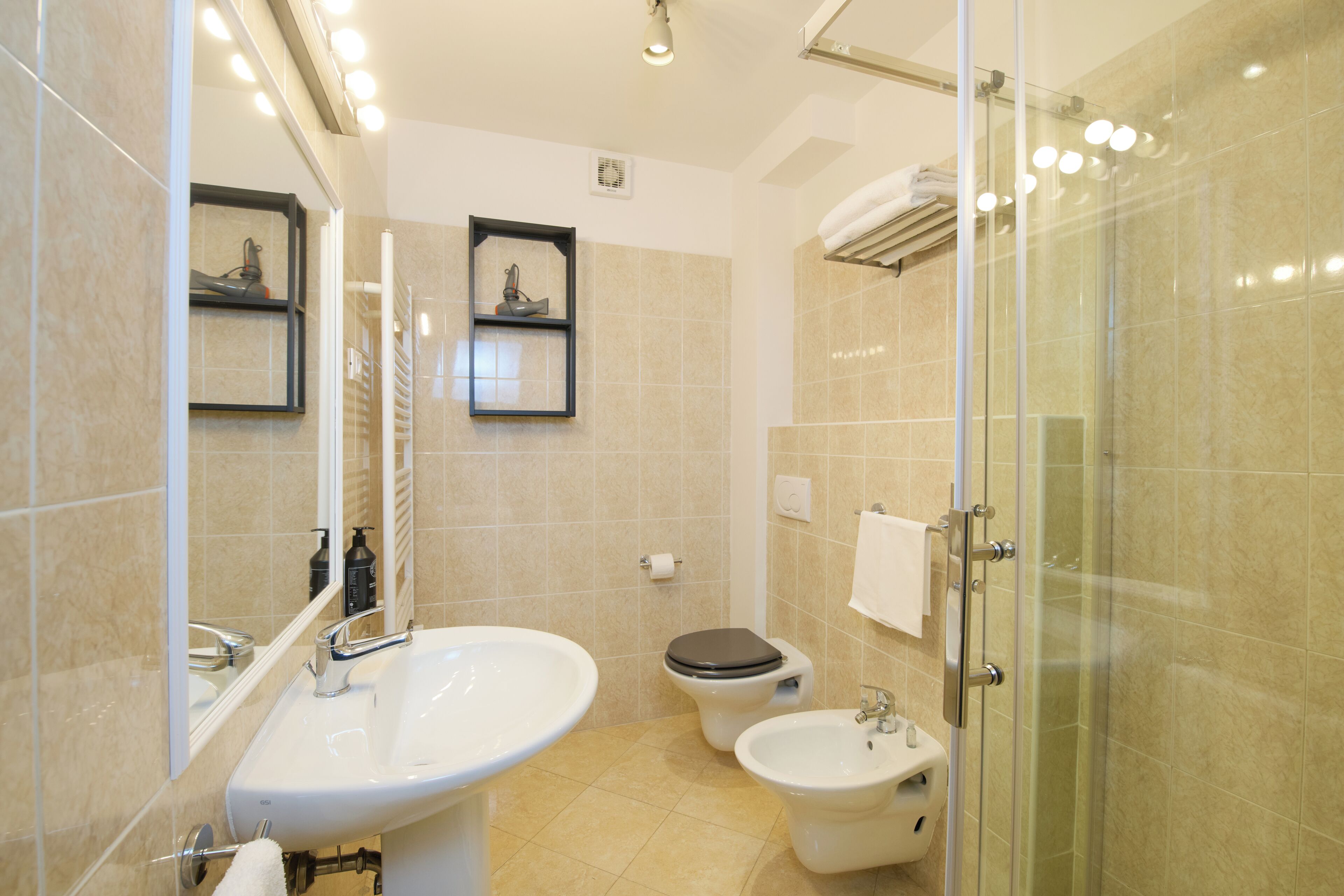 A modern bathroom with a sink, toilet, bidet, and glass shower enclosure.