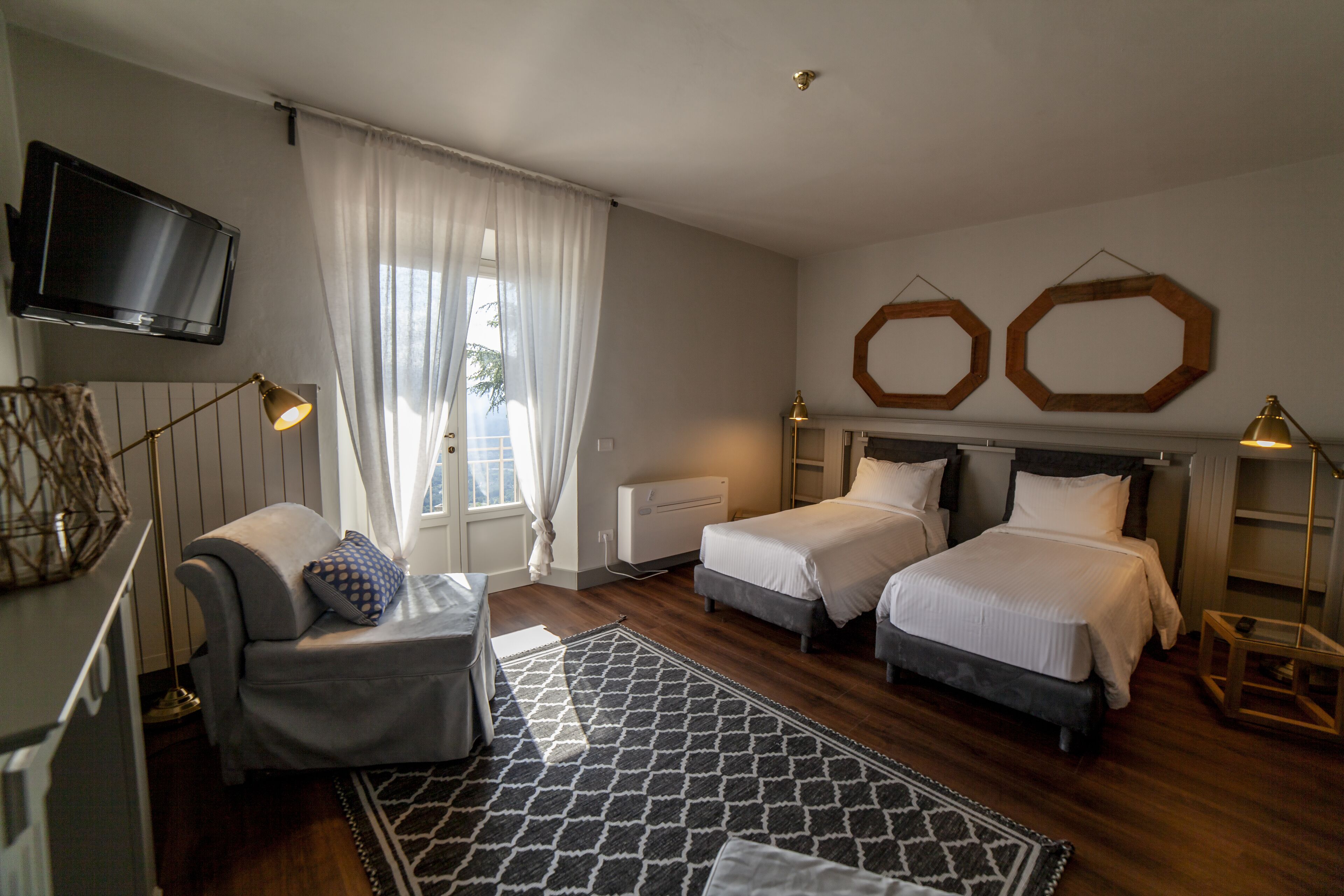 A hotel room with two beds, a TV, and a desk.